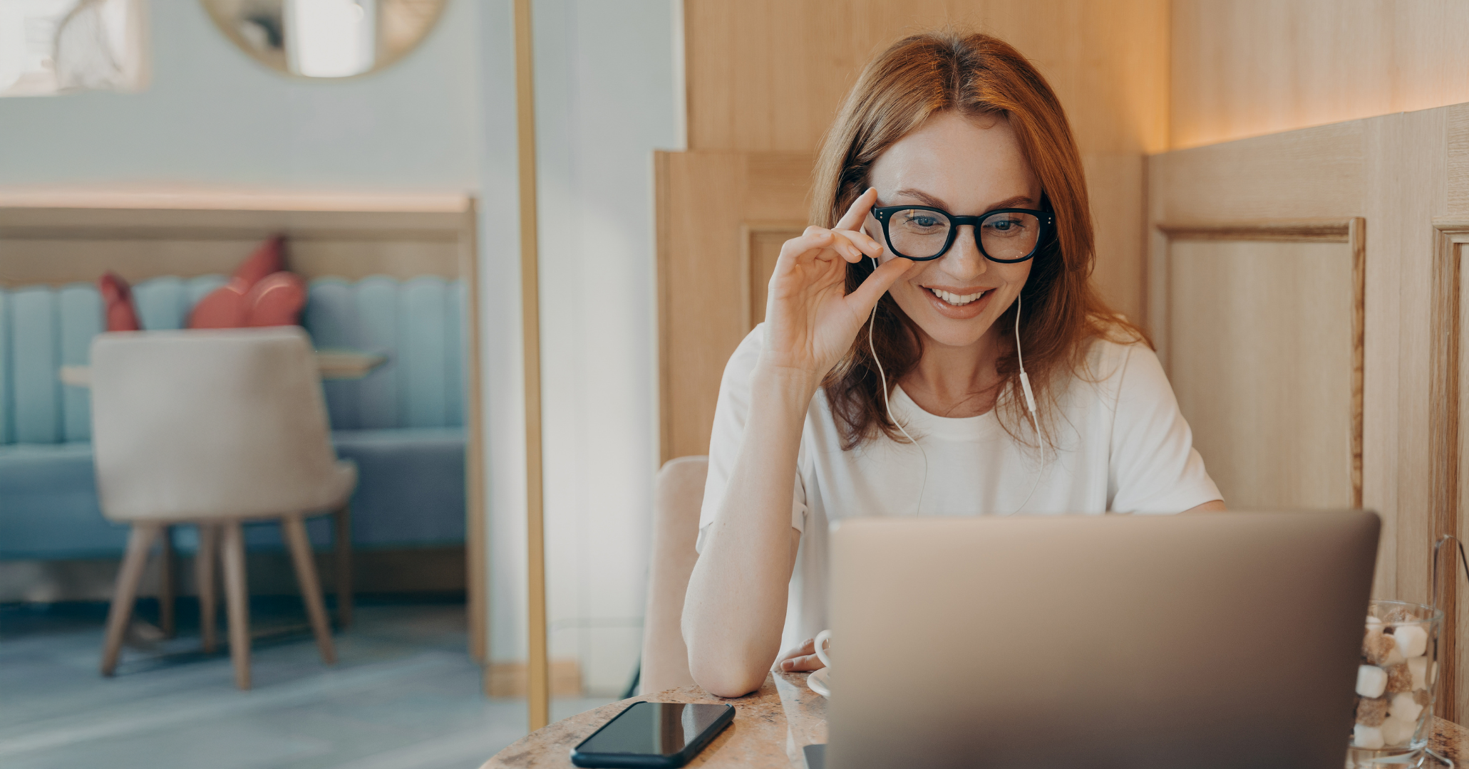 Uśmiechnięta kobieta pracująca przy laptopie w przytulnej kawiarni – symbol satysfakcji, jasności i planu po sesji Pinterest Express.