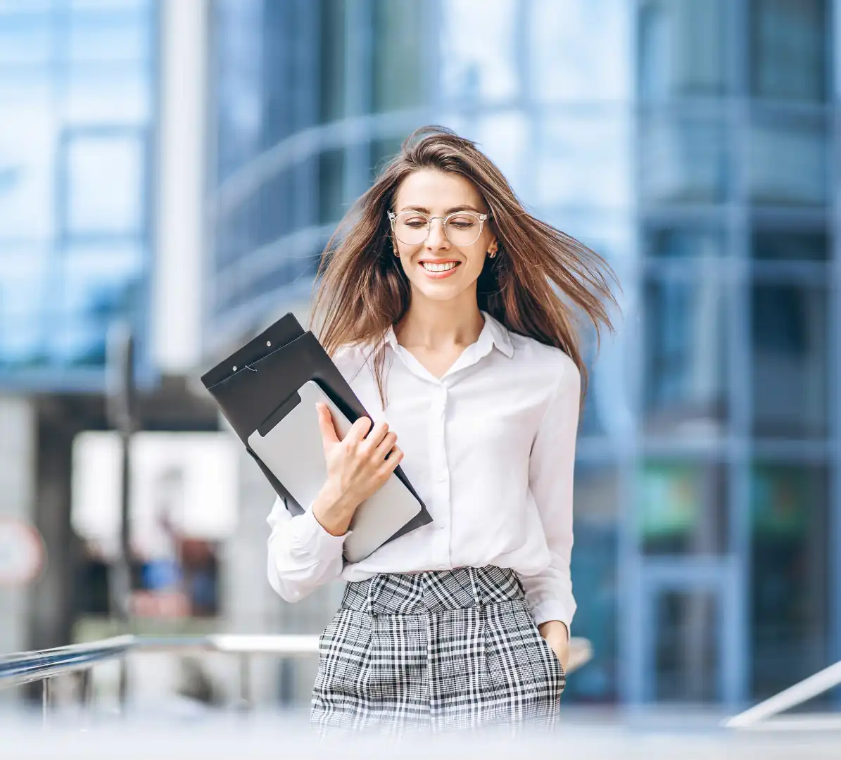 Kobieta z uśmiechem idąca z laptopem i dokumentami w dłoni – symbol gotowości do działania po sesji Pinterest Express.